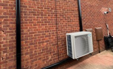 An electrician is inspecting an AC unit